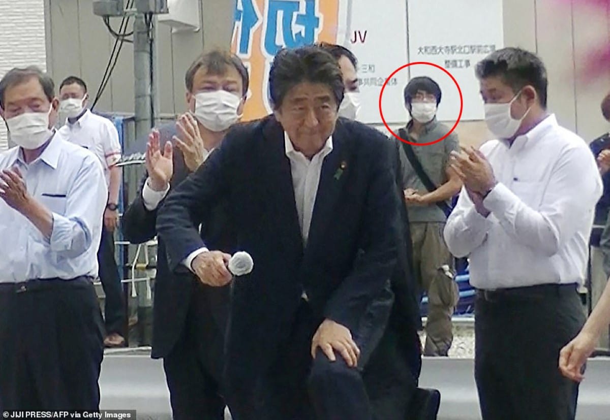 Shinzo Abe y su asesino al fondo