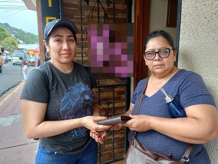 La señora de gorra recibe de parte de la señora de lentes la cartera con un mil dólares que dejó olvidada en un taxi en Matagalpa